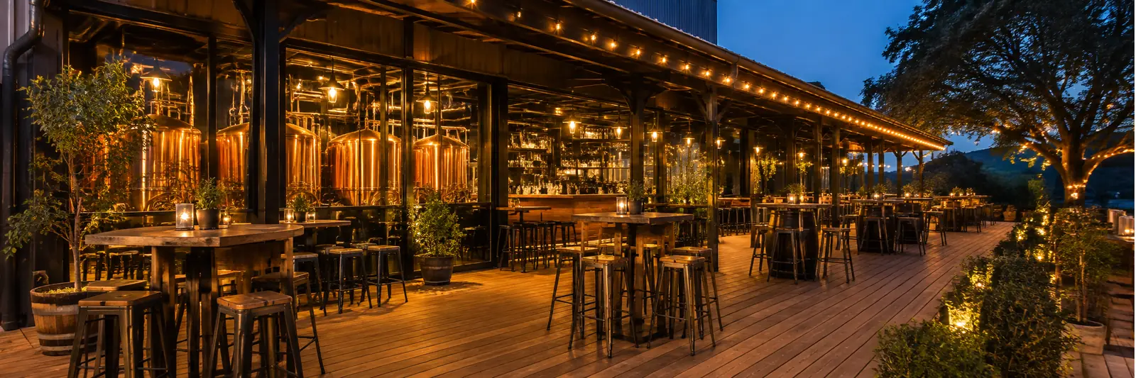 Illustration of a craft brewery taproom terrace at dusk, with copper brewing tanks visible behind glass and warm string lights over wooden tables.